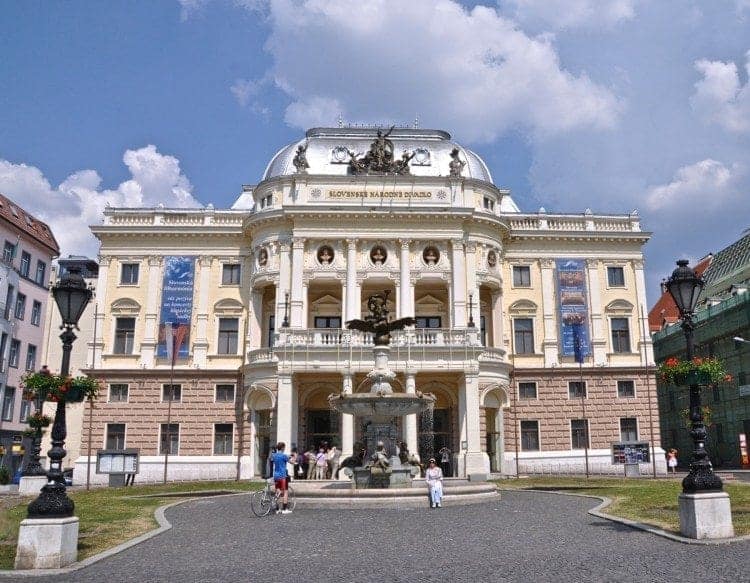 Bratislava National Theatre with people milling about the entrance and elaborate fountain.