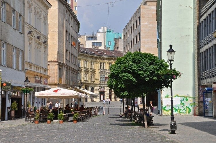 Cafe in city center, tree-lined street in Bratislava with outdoor restaurants with umbrellas.