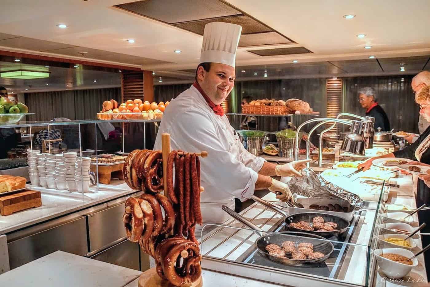 Chef serving dinner on Bavarian night, with pretzels and sausages on display.