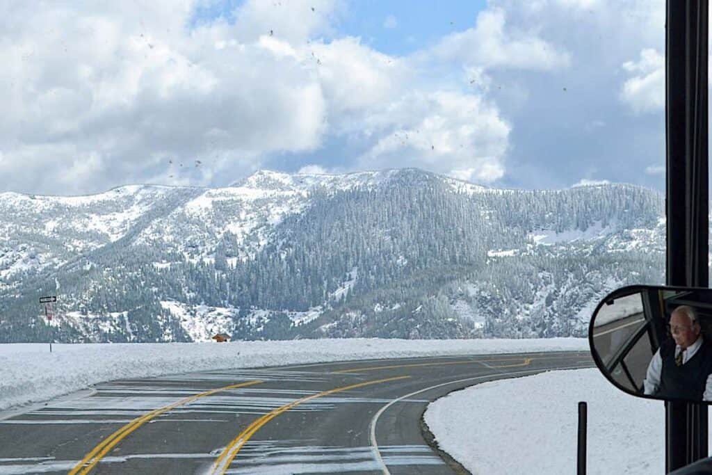 Snow blowing across the mountain road next to the guard rail.