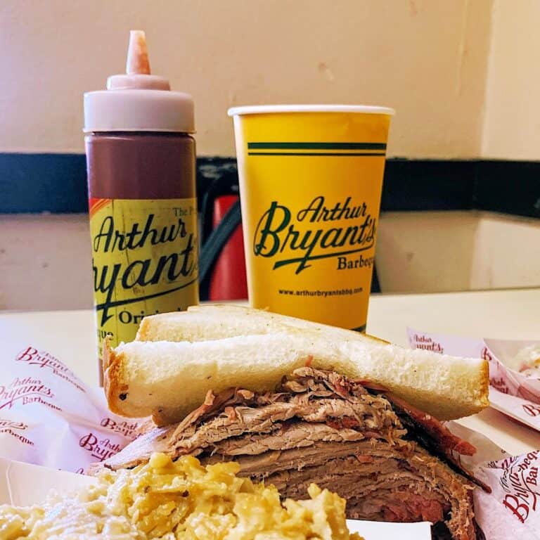 Bottles of Arthur Bryant BBQ Sauces and a brisket sandwich.