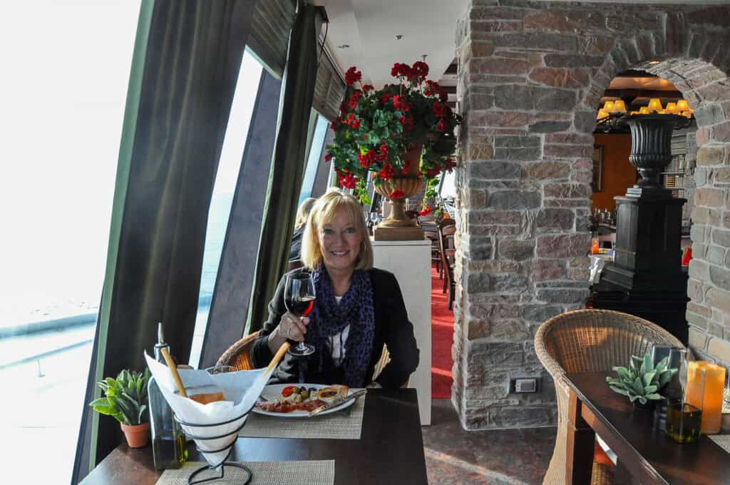 Sherry in the dining room seated by a floor to ceiling