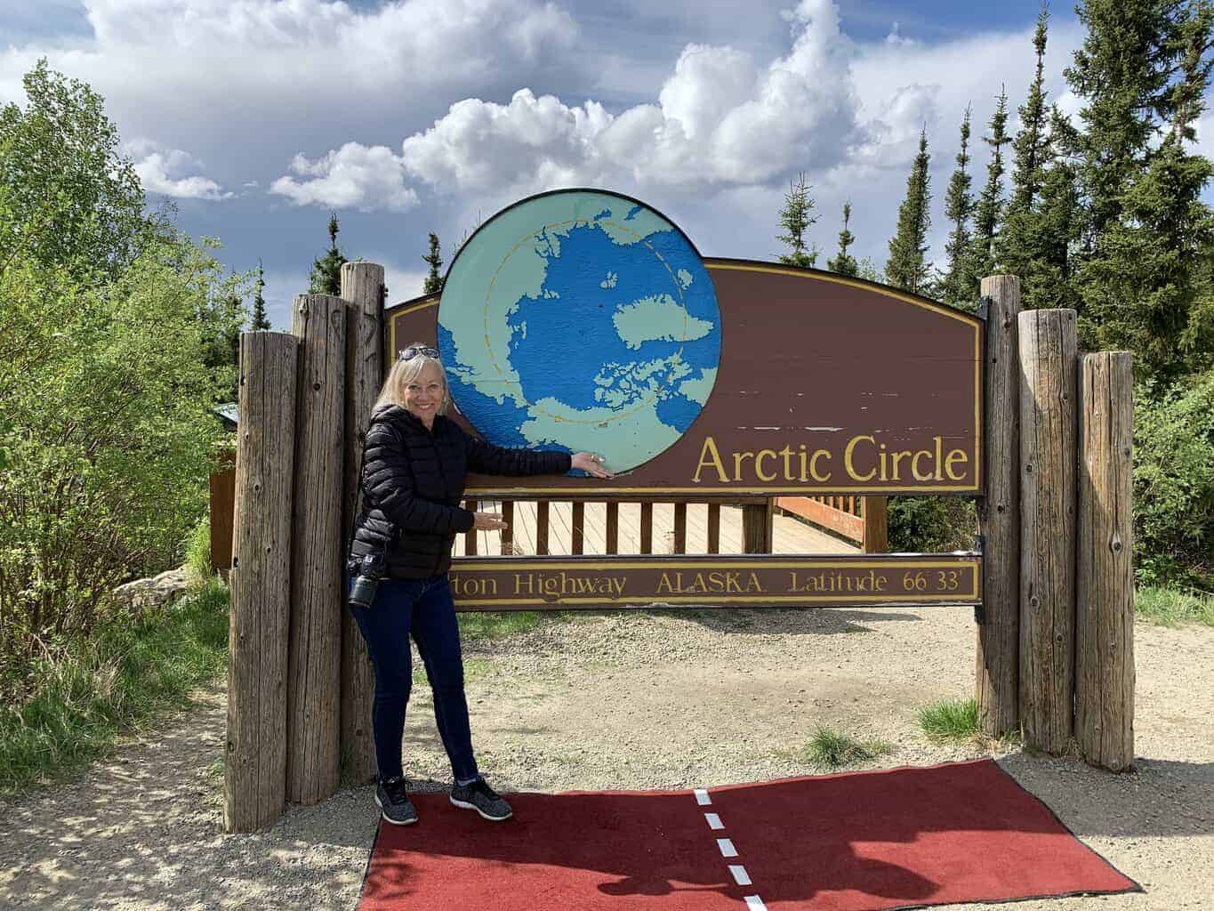 Sherry standing on a red carpet in front of the Arctic Circle welcome sign.