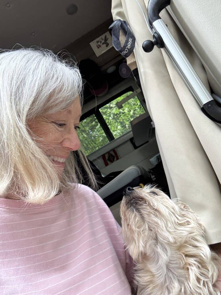 Sherry and Poppy looking at each other while sitting in front of the van.