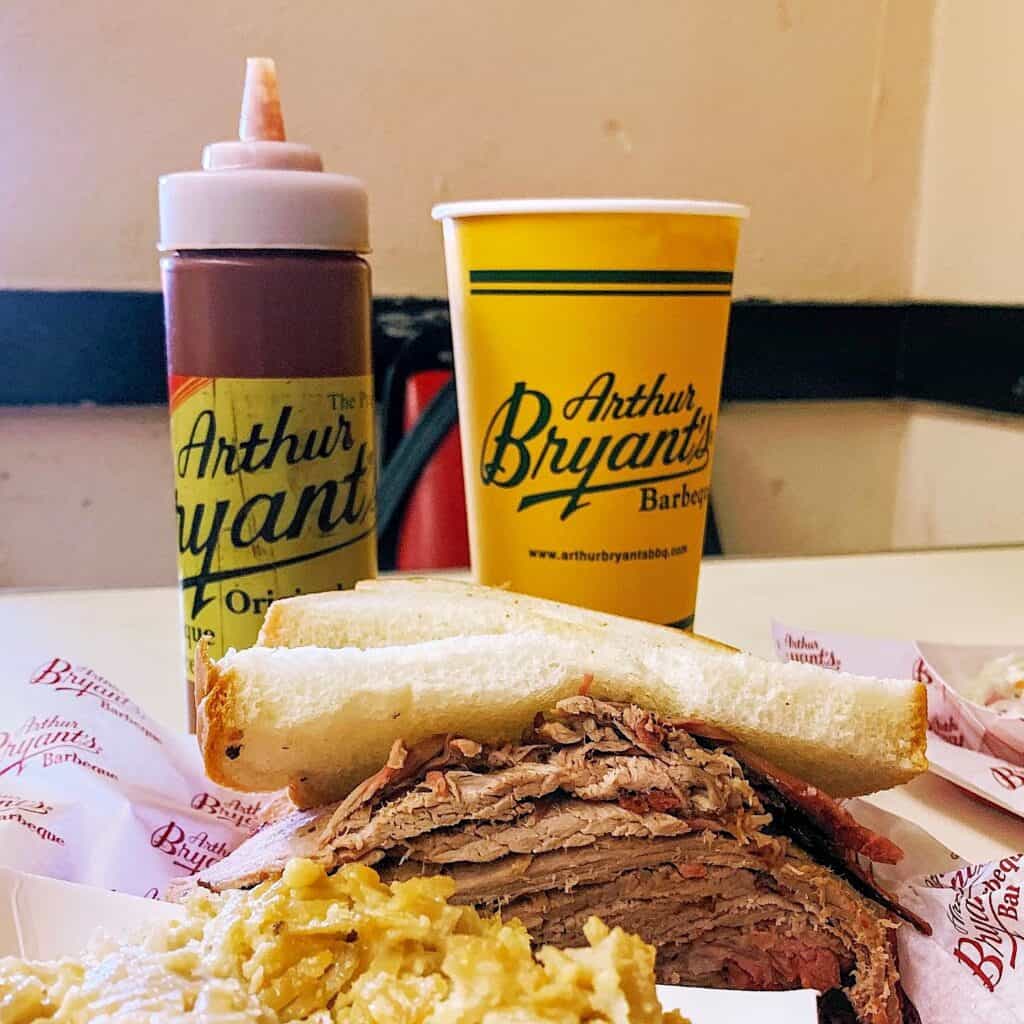 BBQ Brisket sandwich with bottles of bbq sauces.