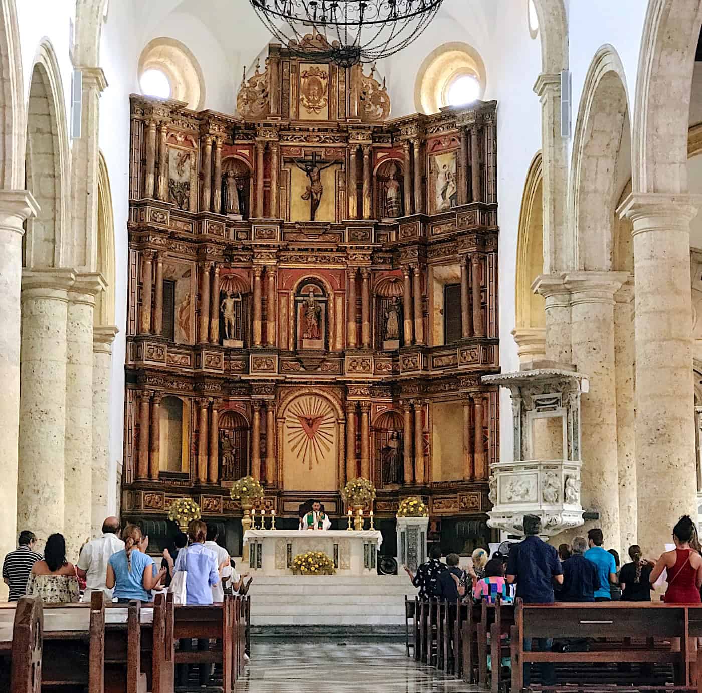 Inside of a Catholic church during mass with rows of casually-dressed worshippers.