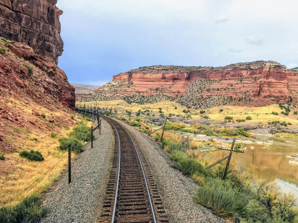 Train tracks on a curve snaking through red rocks canyon.
