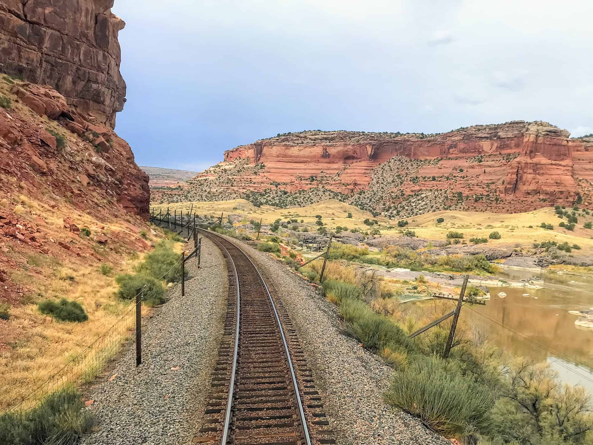 Train tracks traveling between red rock cliffs.