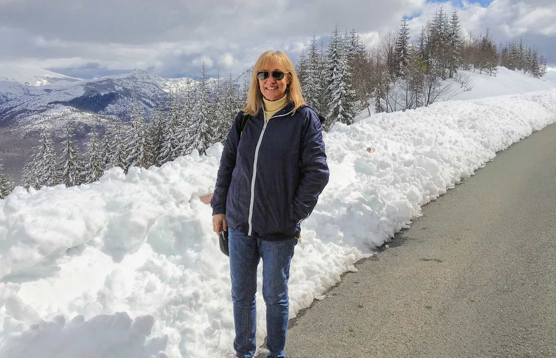 Sherry standing next to a snow bank at the edge of the road at Mount St Helens Park