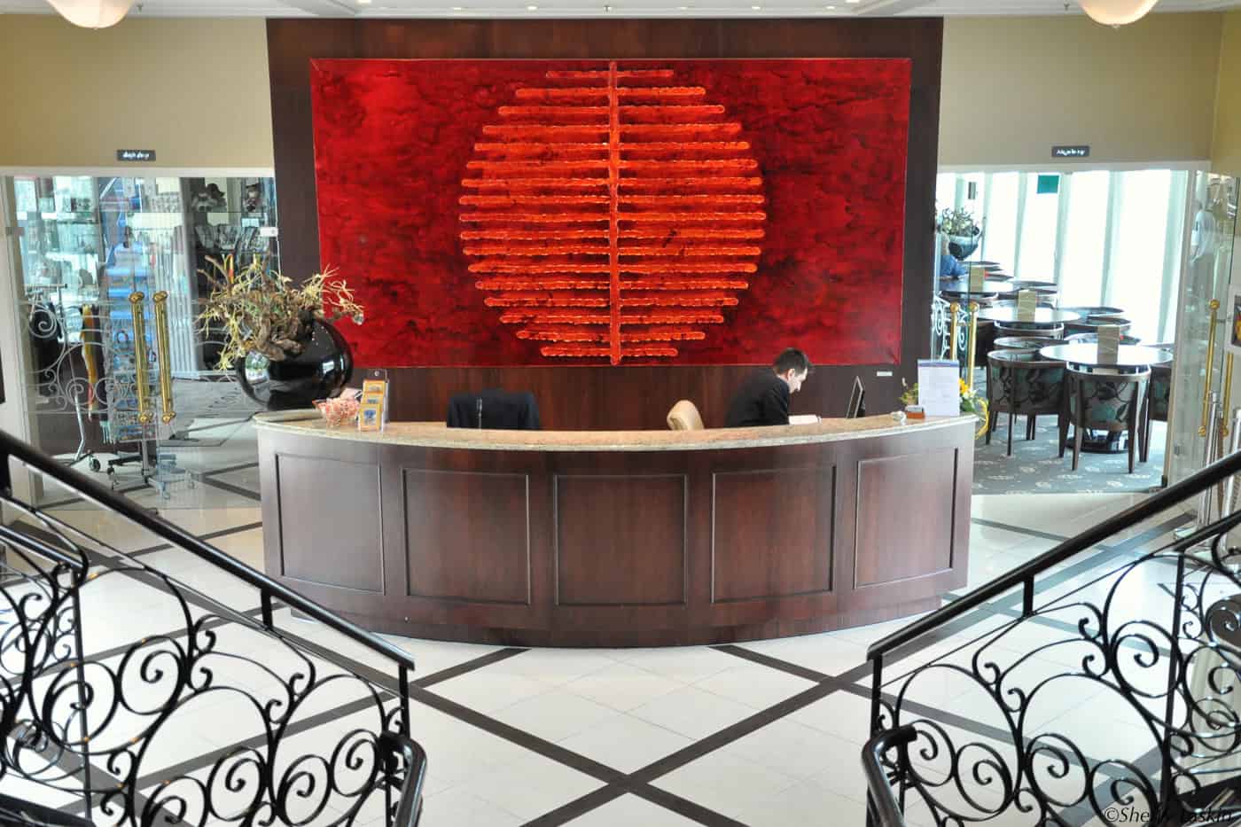Lobby of AmaLegro with a marble-topped reception desk and glass and brass accents on the doors. A black wrought iron handrail led up the flight of stairs.