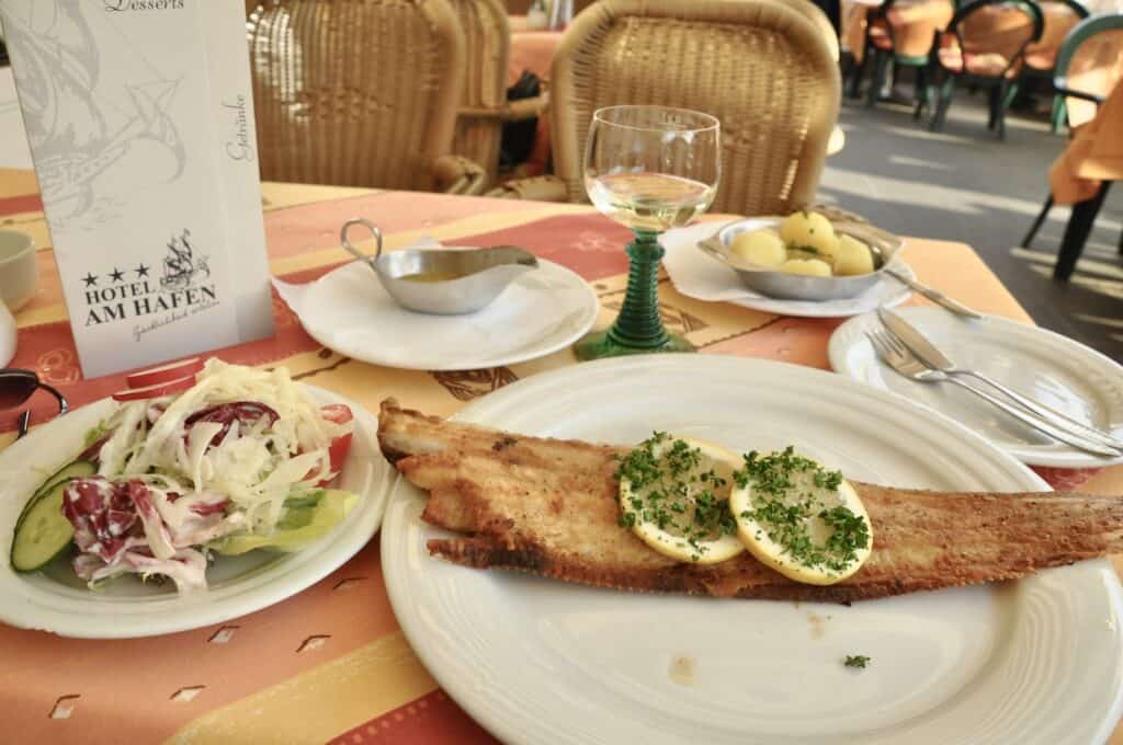 Dover sole dinner on a plate with German slaw and lemons.